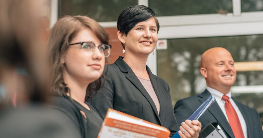 Students holding books and looking off in the distance with a pleasant look on their faces