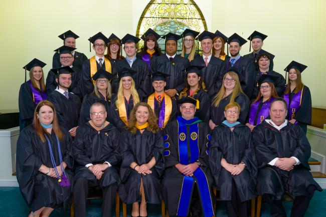 Photo of a graduating class posing in their caps and gowns